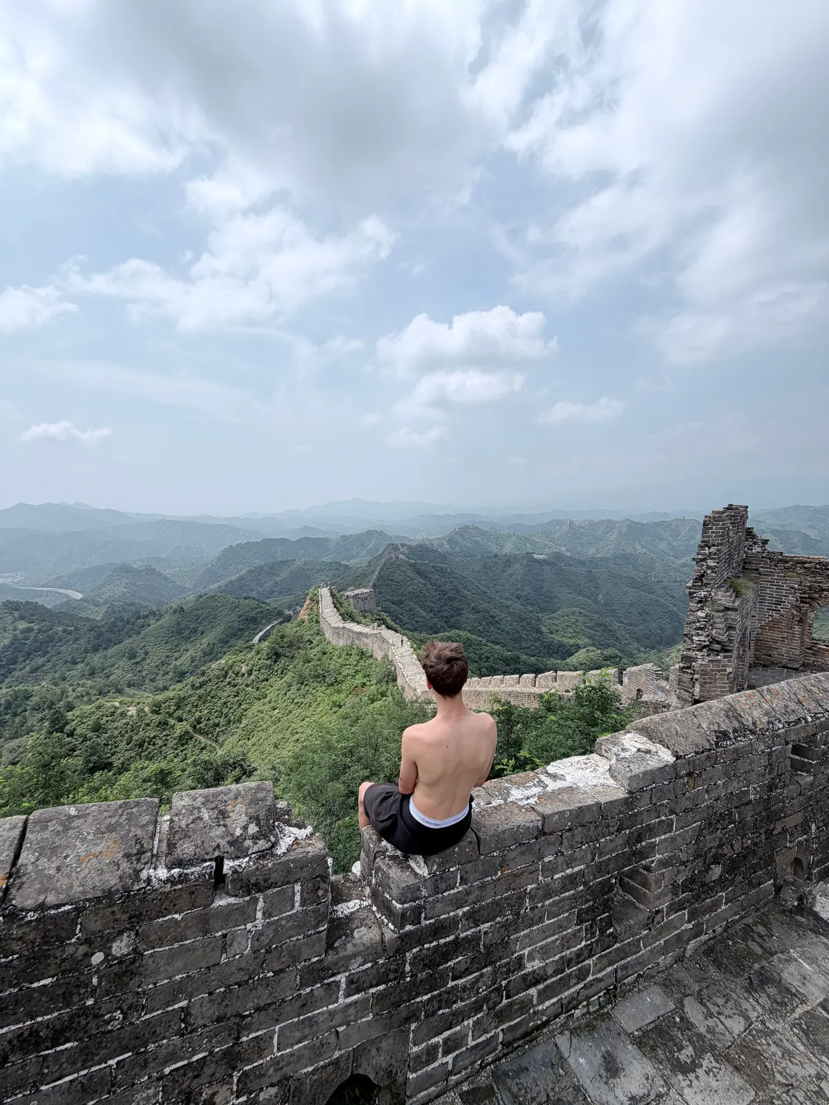 Alexis, assis au sommet du mur, regarde la Muraille s'éloigner sur les crêtes