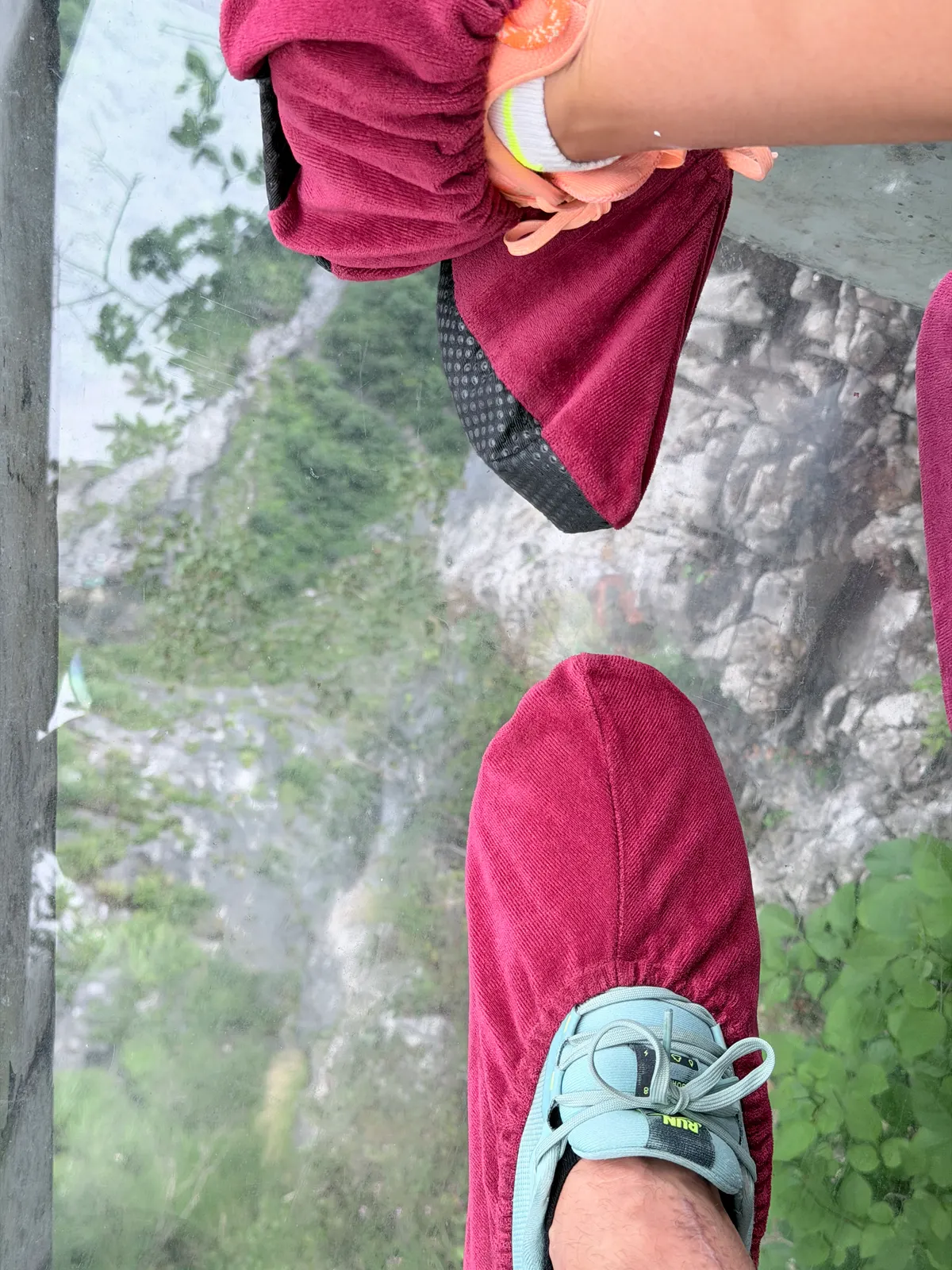 Pieds sur un plancher de verre au-dessus d'une falaise grise vertigineuse