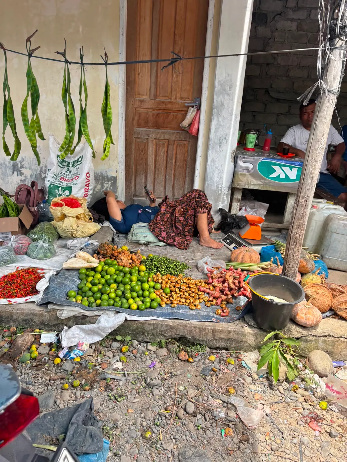 Étal au sol : citrons verts, petai (les « haricots puants »), piments, curcuma et gingembre frais