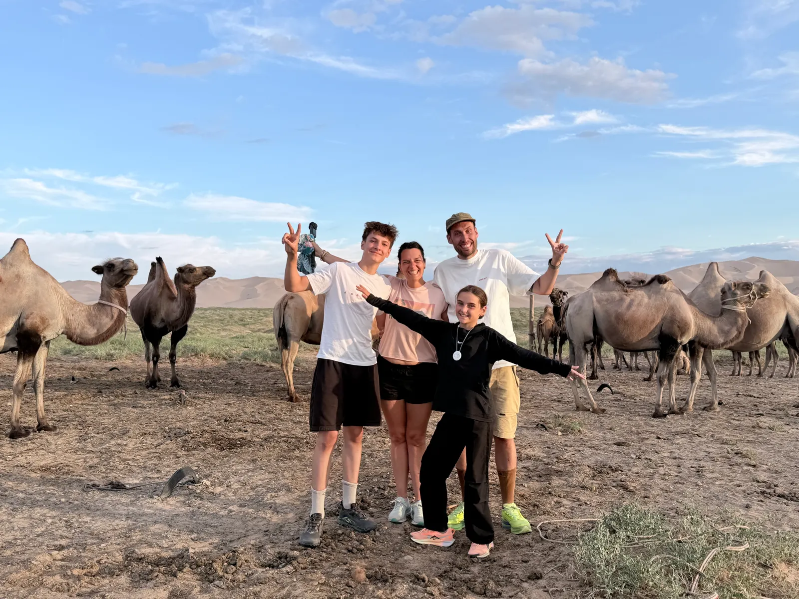 Toute la famille et le troupeau de chameaux de Bactriane au pied des dunes, à l'heure dorée